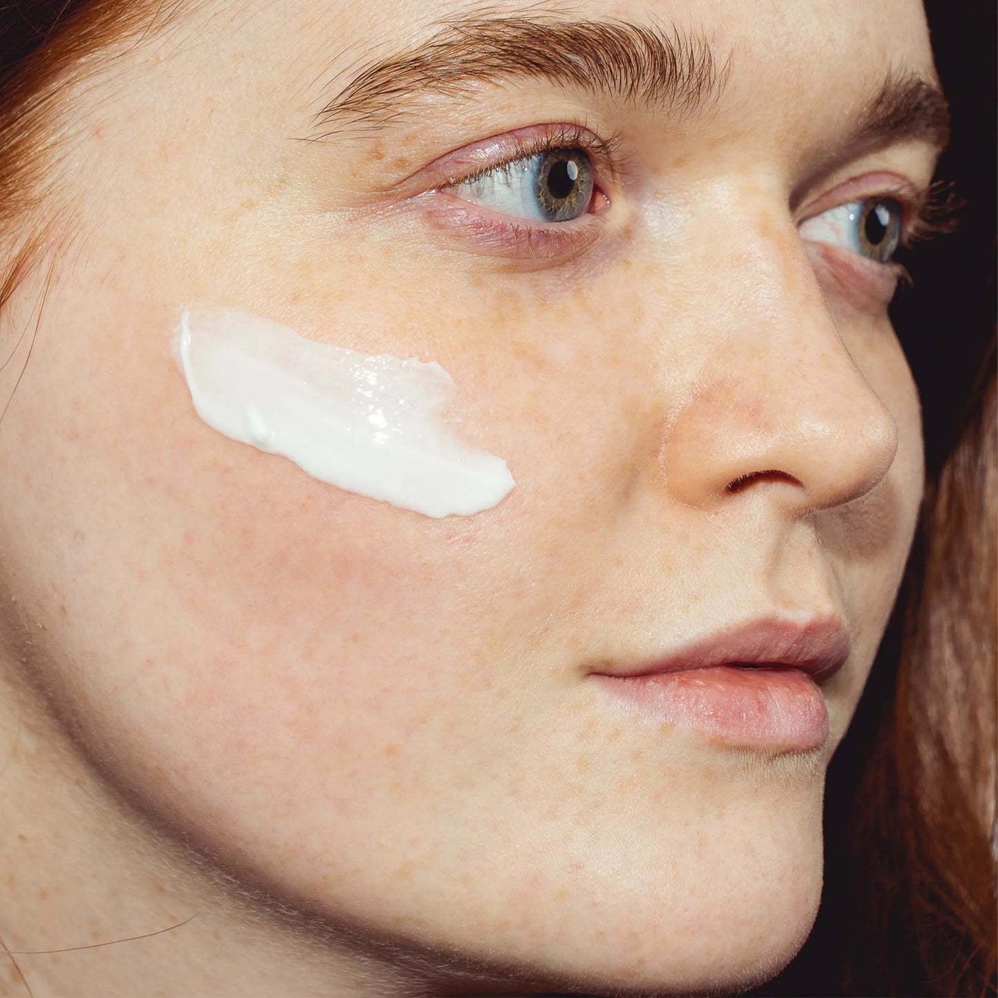 une femme a étalé la crème sur sa joue