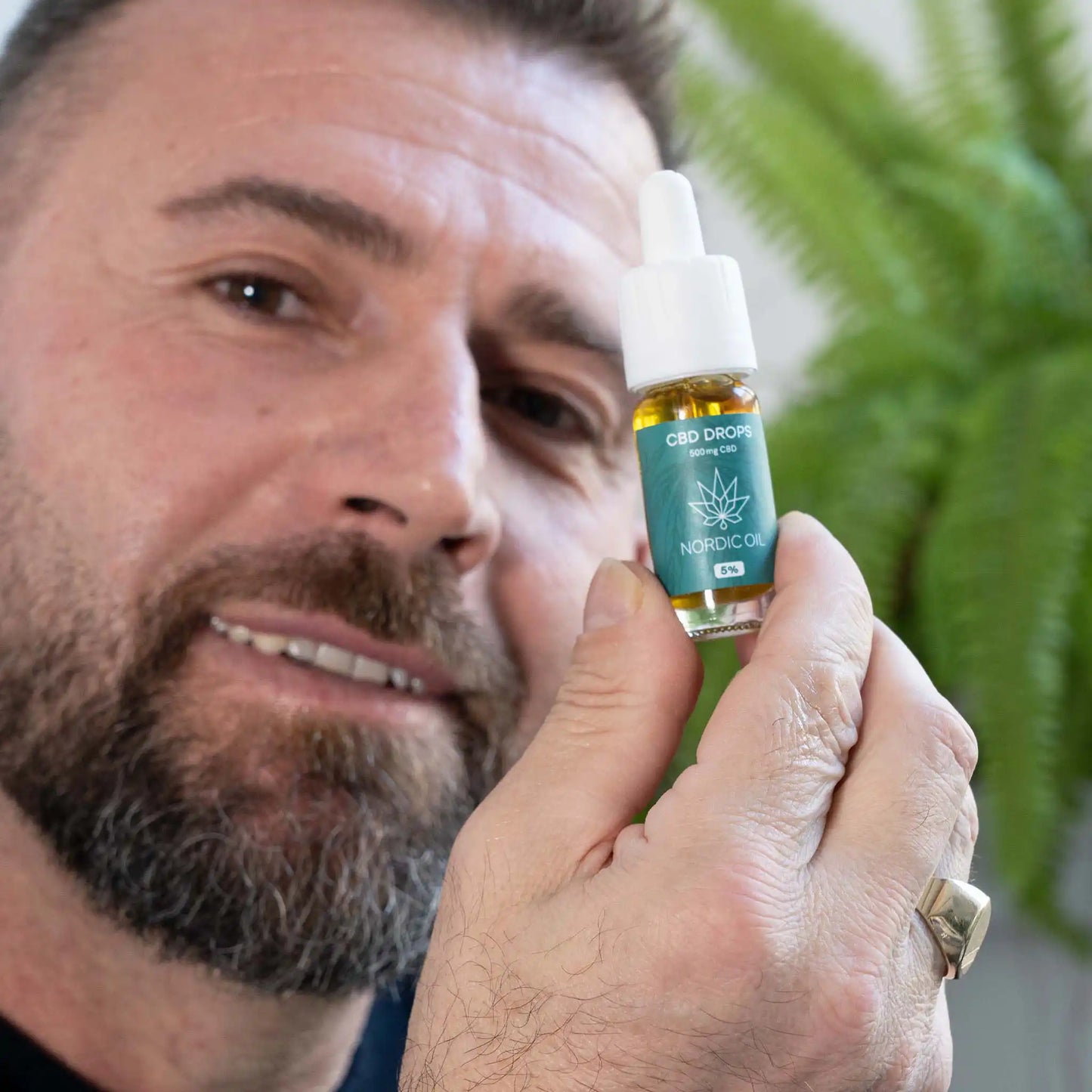 un homme tient l'huile de CBD face à la caméra