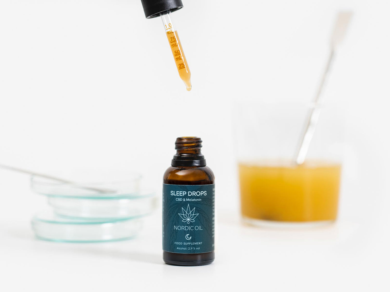 des gouttes de sommeil avec cbd et mélatonine à côté d'un verre de jus de fruit