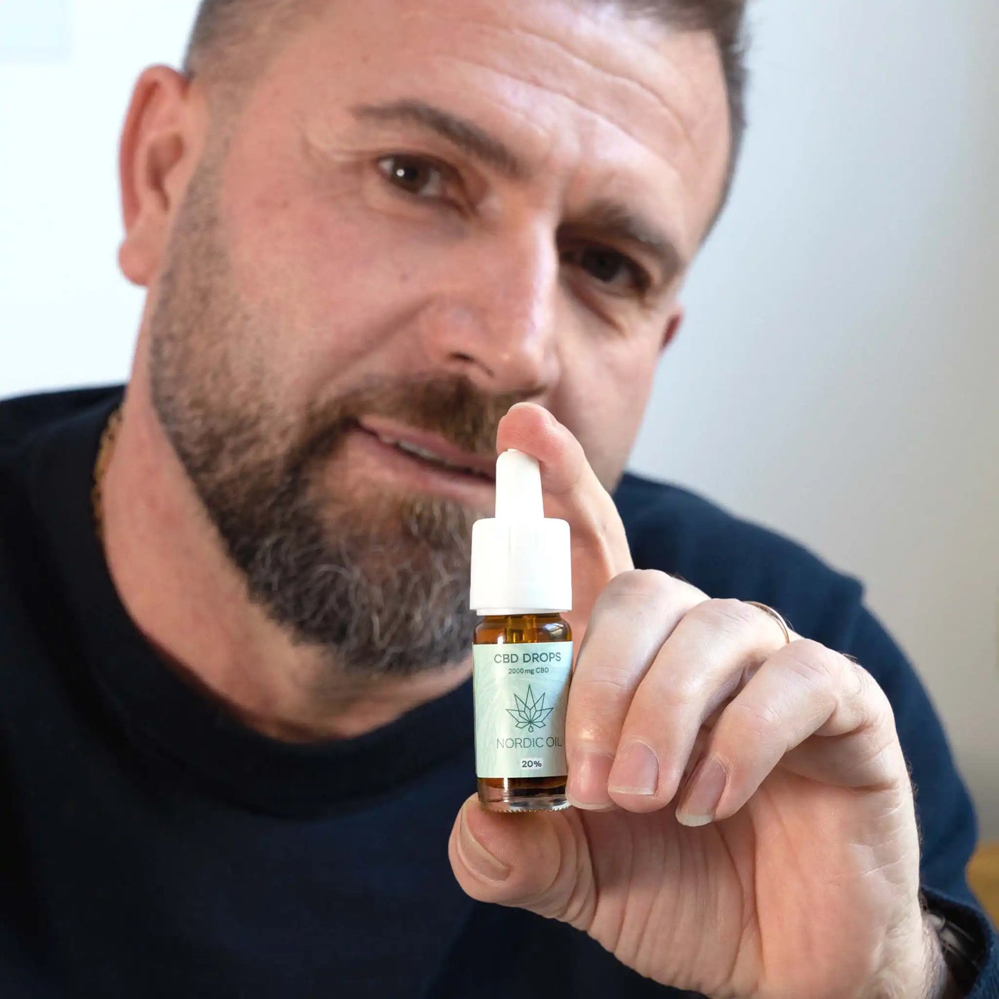 un homme tient l'huile de CBD devant la caméra