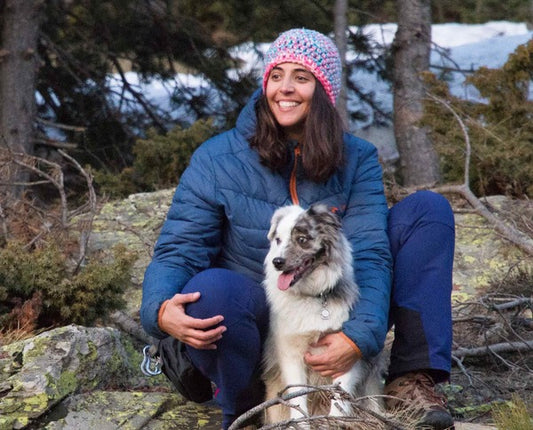 Une femme et son chien sont assis dans les montagnes.