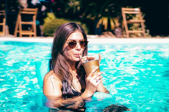 fille sirotant une boisson dans une piscine au soleil