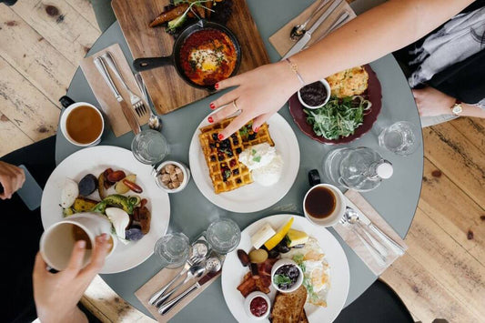 image d'un petit déjeuner sur une table ronde avec plusieurs assiettes contenant divers produits sucrés et salés