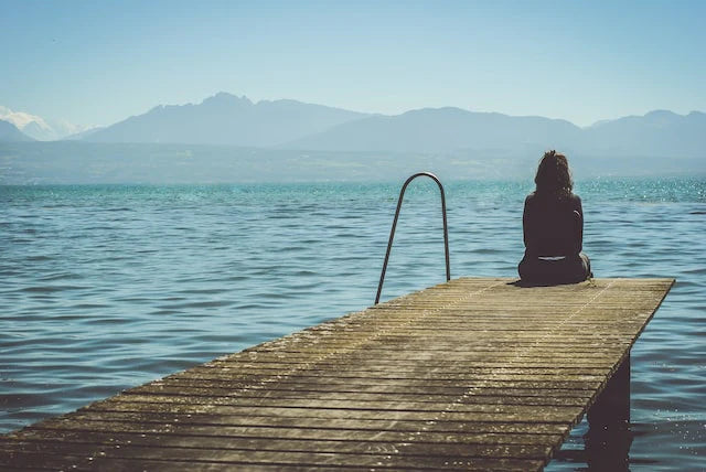 Une femme seule contemplative au-dessus d'un lac