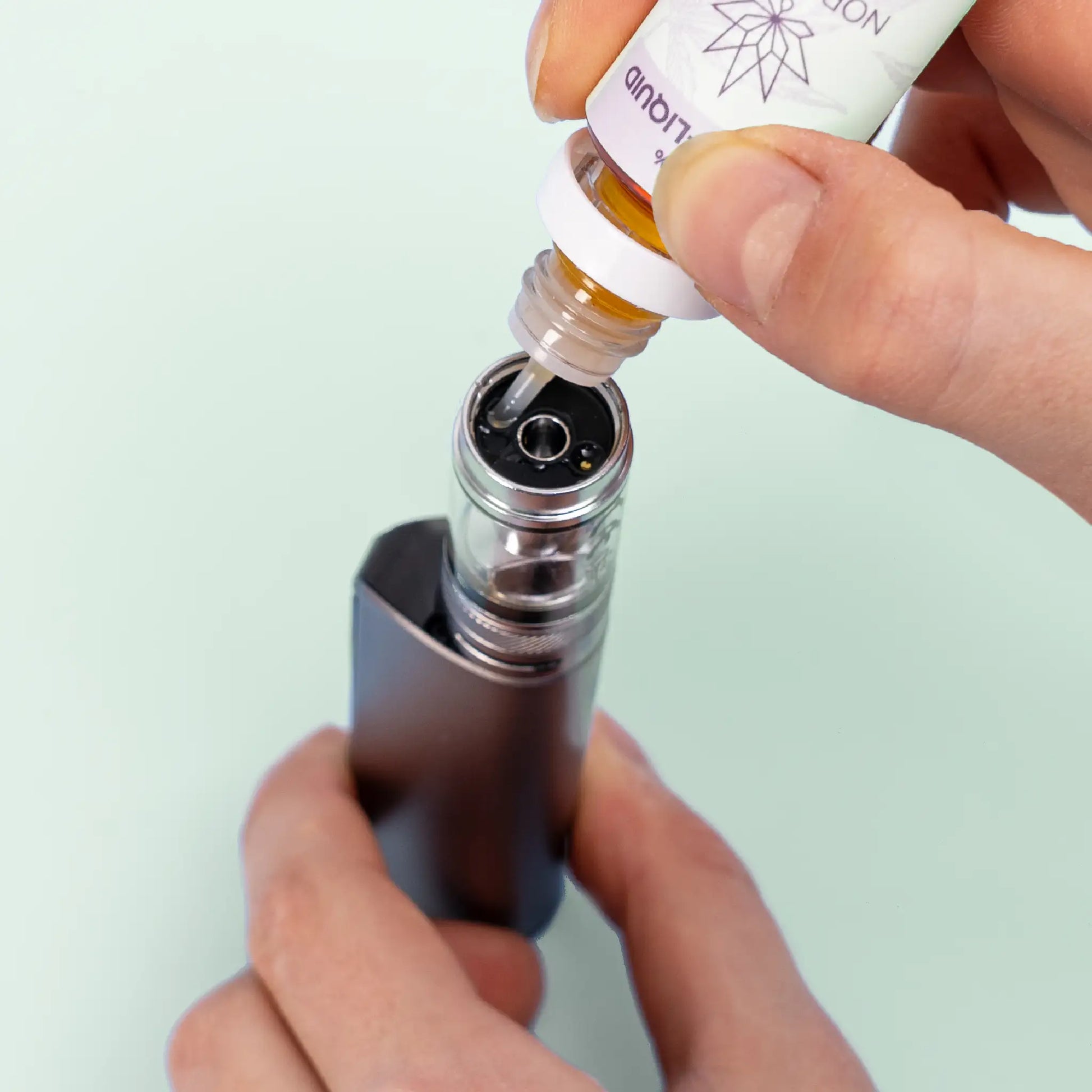 Une personne remplissant une E-cigarette avec Nordic Oil CBD E-Liquid 3% - Raisin & Menthe