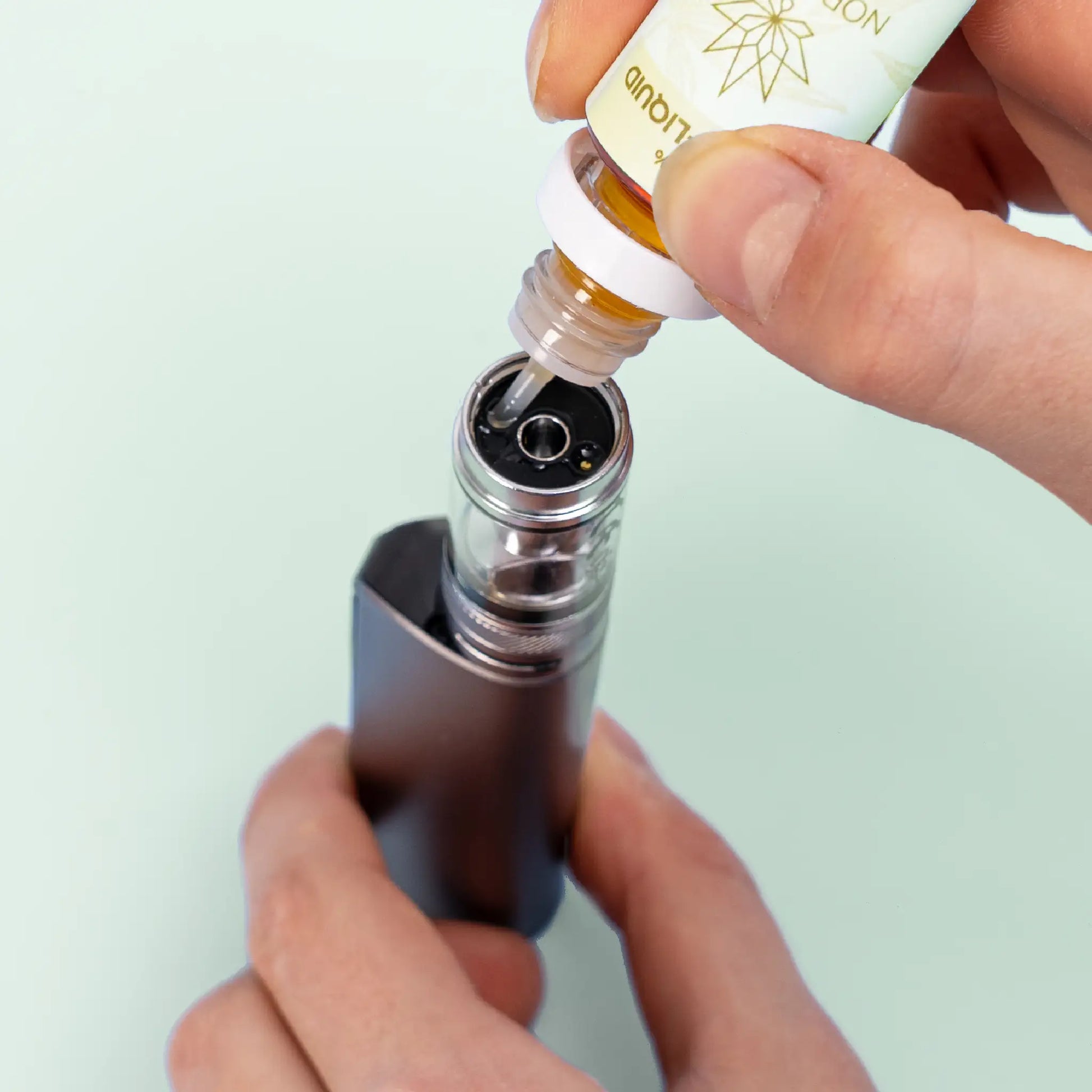 Une personne remplissant une e-cigarette avec Nordic Oil Citron & Menthe E-Liquid 3%.