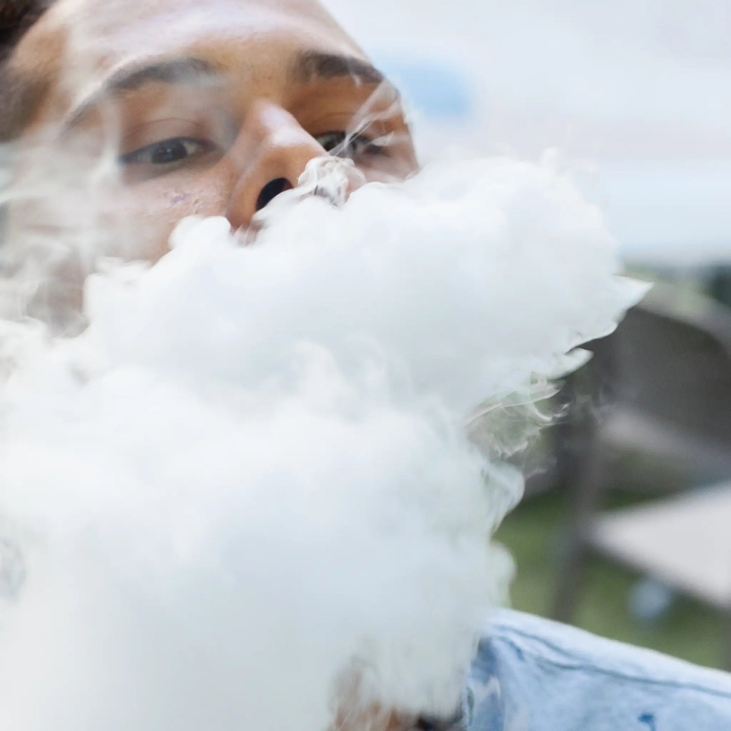 Une personne qui expire la vapeur inhalée d'une E-cigarette remplie de Nordic Oil CBD E-Liquid