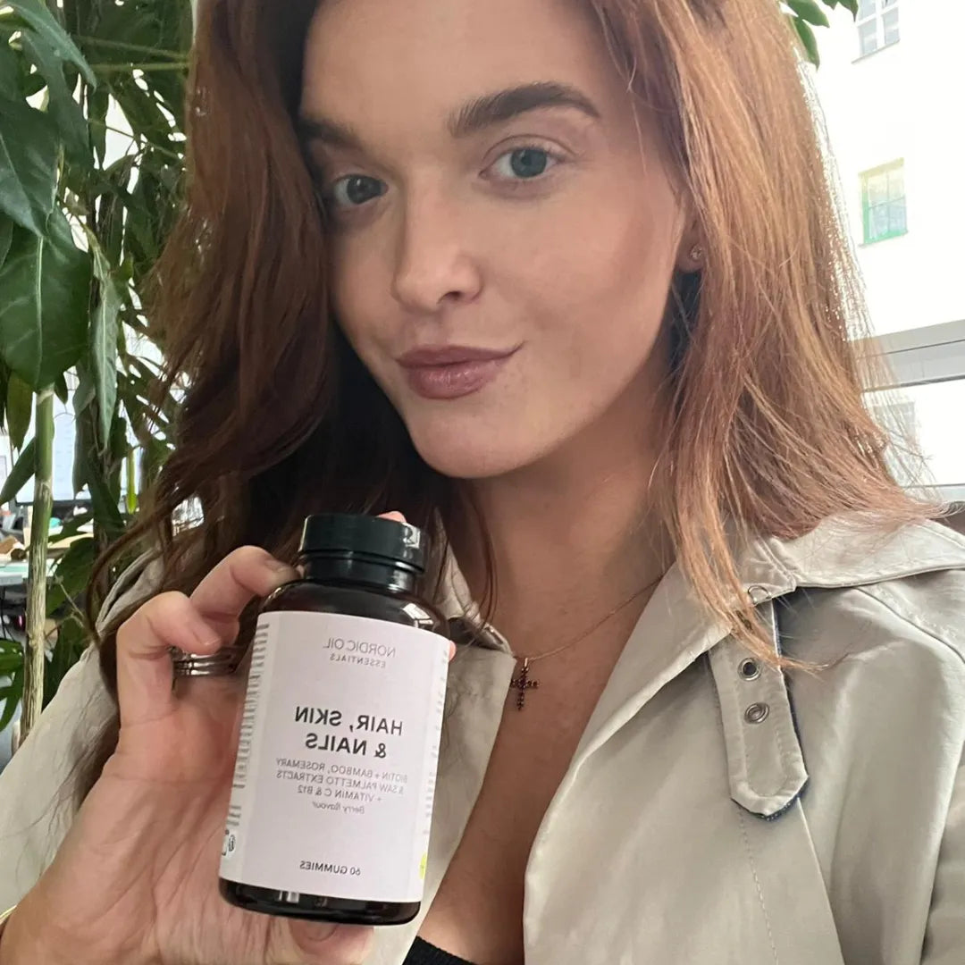 Femme tenant une bouteille de compléments Hair, Skin & Nails de Nordic Oil.