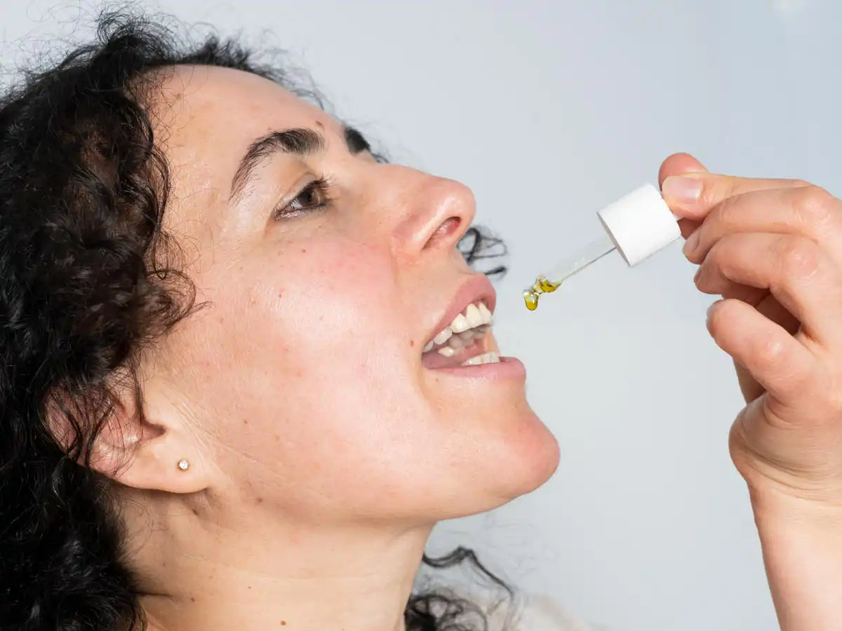 Une femme met de l'huile de CBD dans sa bouche